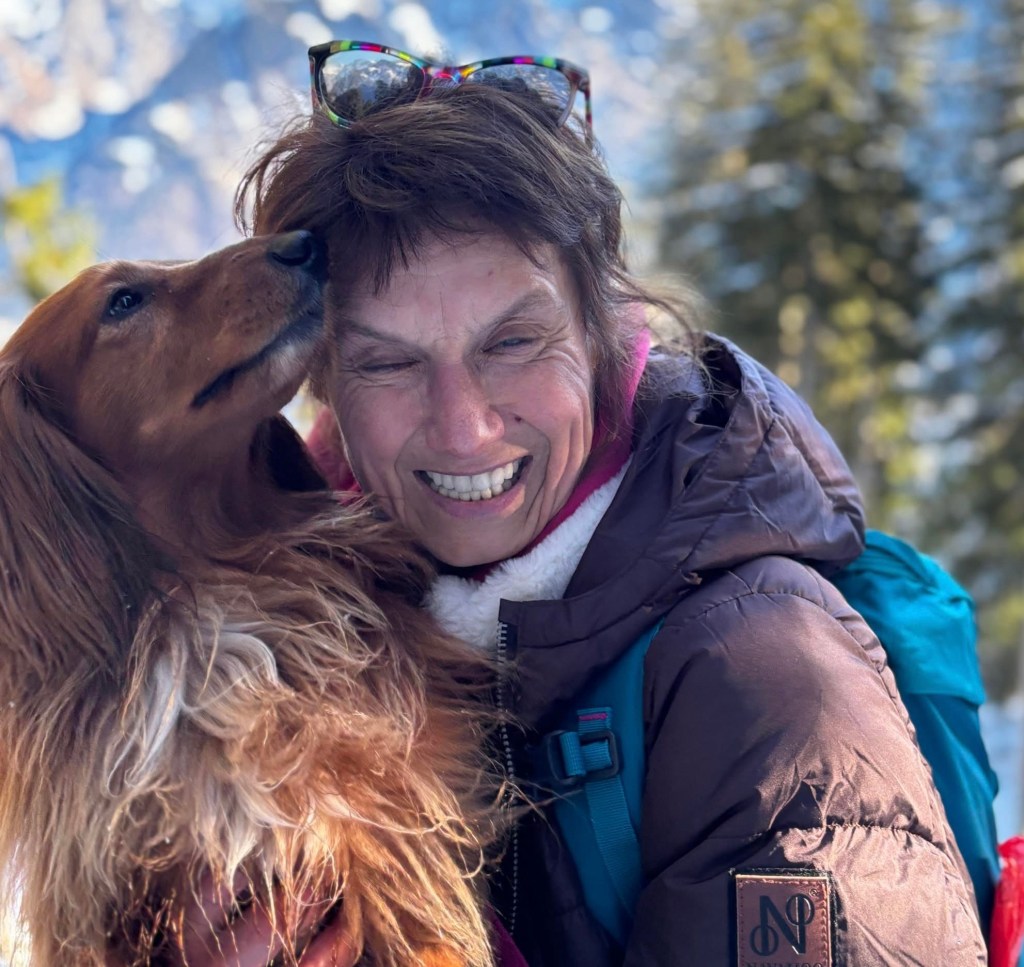 Glückliche Frau mit Langhaardackel auf dem Arm